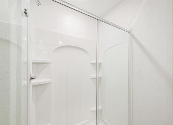 a white bathroom with a glass shower door at The Village at Caney Mills, Texas, 77303