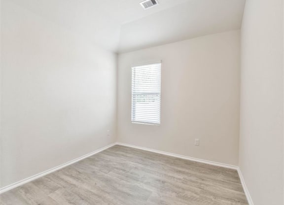 an empty room with a window and wood flooring at The Village at Caney Mills, Texas, 77303