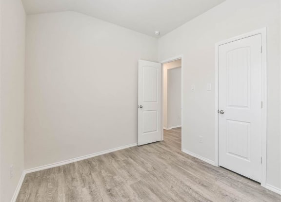 a bedroom with two doors and a door to a closet at The Village at Caney Mills, Texas