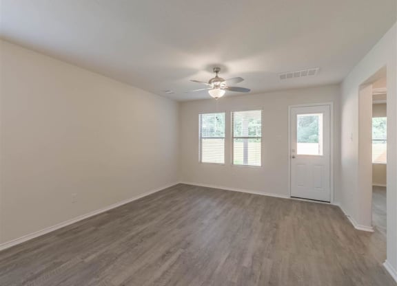 an empty living room with a ceiling fan and a door at The Village at Caney Mills, Conroe, Texas