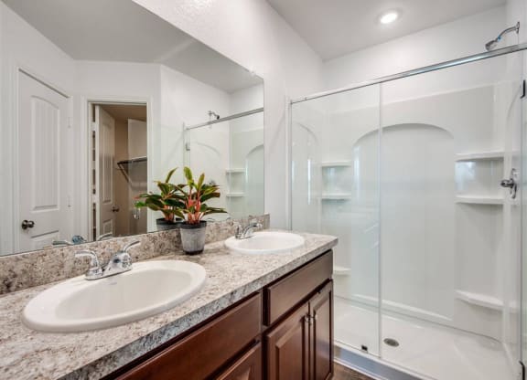 a bathroom with two sinks and a shower at The Village at Caney Mills, Conroe