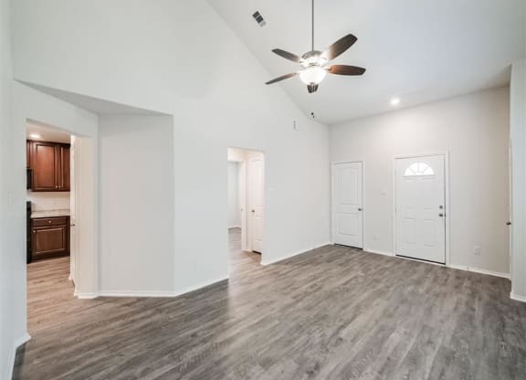 the living room and kitchen of a new home with a ceiling fan at The Village at Caney Mills, Conroe, 77303