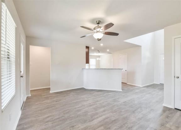 an empty living room and kitchen with a ceiling fan at The Village at Caney Mills, Texas