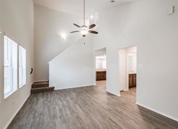 an empty living room with white walls and a ceiling fan at The Village at Caney Mills, Texas, 77303