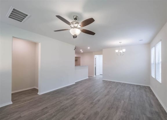 an empty living room with a ceiling fan and a kitchen at The Village at Caney Mills, Conroe, Texas
