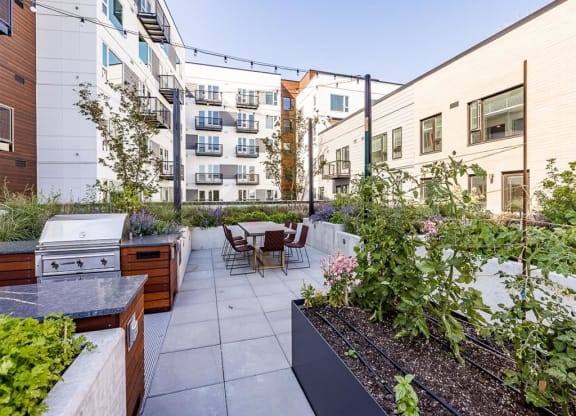 a patio with a grill and a table and chairs