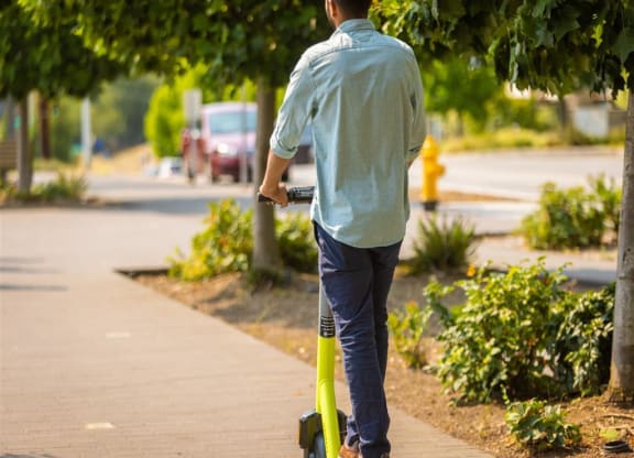 a man riding a scooter down a sidewalk