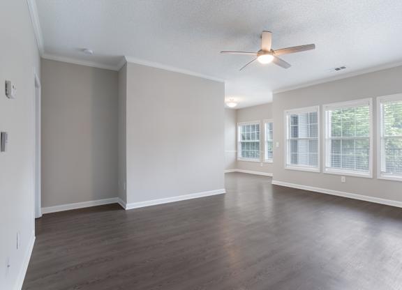Empty room with a ceiling fan and large windows.