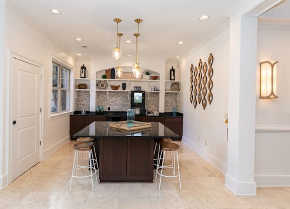 a kitchen with white walls and tiles flooring and a large center island with a black counter at Westmount at Ashwood, Georgia