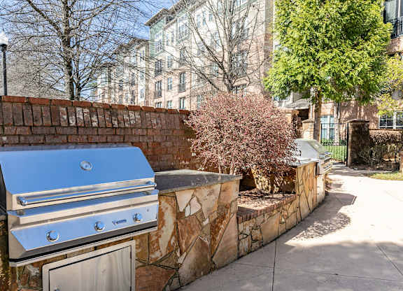 an outdoor kitchen with a grill and a tree in front of a brick wall at Westmount at Ashwood, Georgia