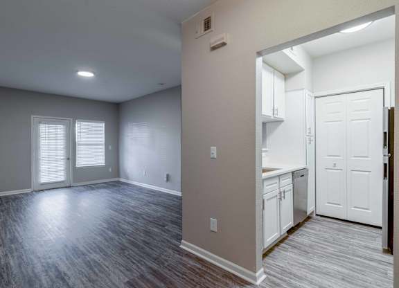 an empty living room and kitchen with white doors