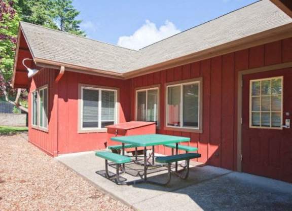 A red building with a green picnic table in front.