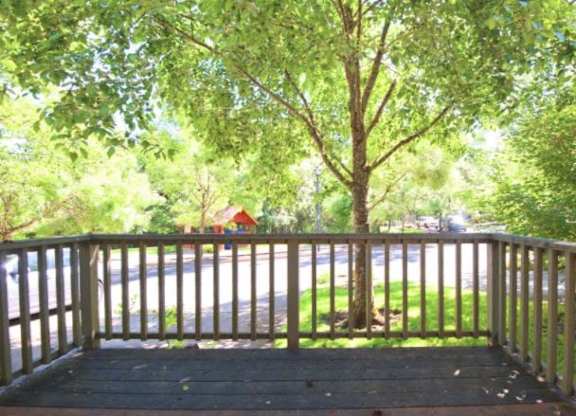 A wooden deck with a railing and a tree in the middle.