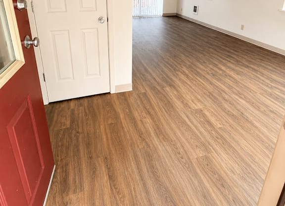 A room with a white door and wooden flooring.