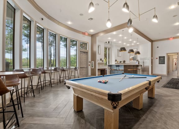 a pool table in the clubhouse of a community with tables and chairs at Mission Gate, Plano