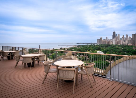 a deck with tables and chairs overlooking a city and the ocean at the Belden Stratford in Chicago, Illinois