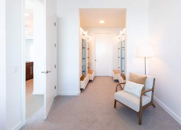A white chair with a pillow sits in a hallway.