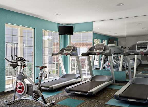 a gym with treadmills and exercise bikes in a room with windows  at Verona, Littleton, CO, 80123