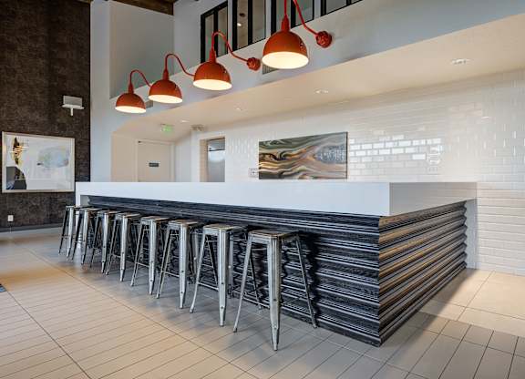 a long bar with stools in front of a white counter in a hotel lobby at Ashford Belmar Apartments, Lakewood, Colorado
