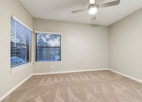 an empty living room with a large window and a ceiling fan at Ashford Belmar Apartments, Lakewood, 80226
