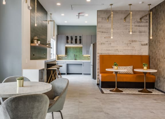 a dining area with tables and chairs and a kitchen in the background at Carrington at Barker Cypress, Cypress, TX