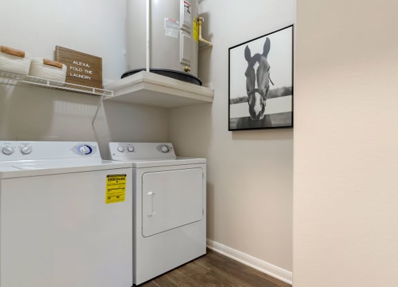 a laundry room with a washer and dryer and a painting on the wall at Madison on the Meadow, Stafford, Texas