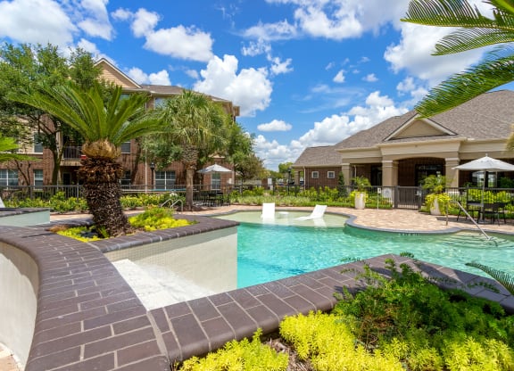 a swimming pool with the resident clubhouse in the background at Madison on the Meadow, Stafford, TX, 77477