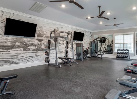 a gym with weights and a tv on the wall at Reserve by the Lake, Houston, Texas