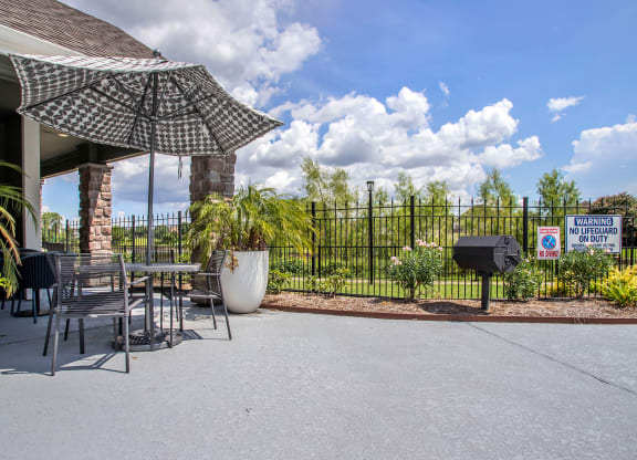 a patio with a table and chairs and an umbrella and a grill at Reserve by the Lake, Houston, TX, 77084