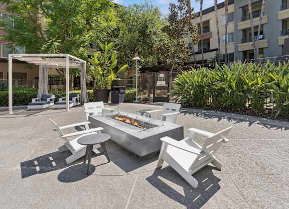 A white outdoor barbecue grill with chairs and a table is set up in a courtyard at The Kitt at Warner Center Apartments, Woodland Hills, California