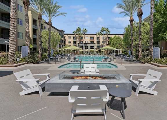 A pool surrounded by palm trees and chairs at The Kitt at Warner Center Apartments, California, 91303