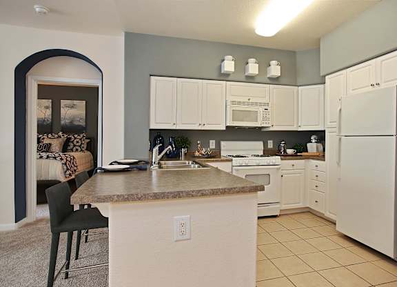 A kitchen with white appliances and a countertop with a sink at The Kitt at Warner Center Apartments, Woodland Hills, California