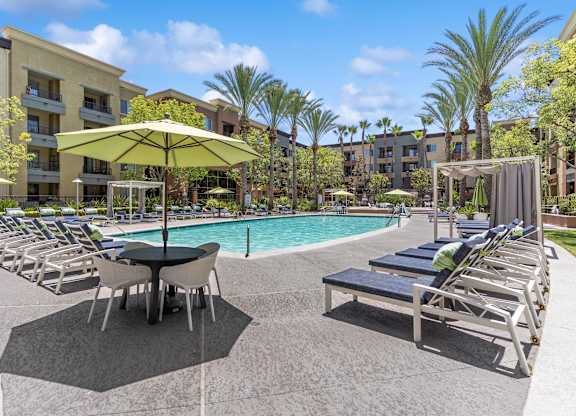 A poolside area with sun loungers and umbrellas at The Kitt at Warner Center Apartments, Woodland Hills