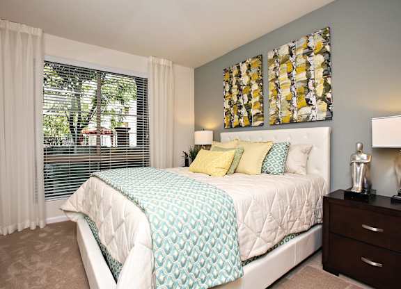 A bedroom with a large bed and a window with blinds. at The Kitt at Warner Center Apartments, Woodland Hills, California