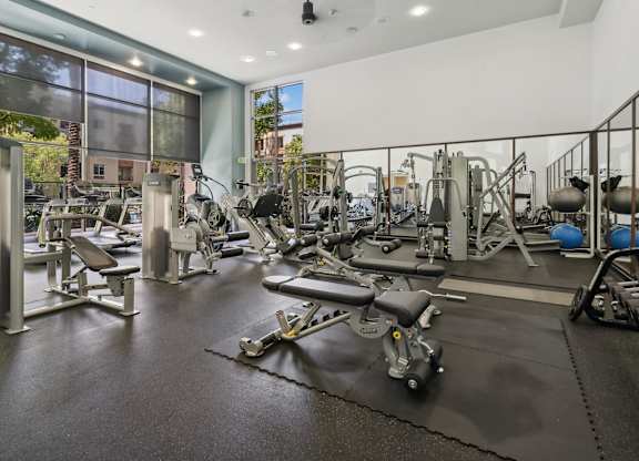 A gym with a variety of equipment including weights and machines. at The Kitt at Warner Center Apartments, California