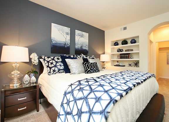A bedroom with a bed, nightstand, and wall art at The Kitt at Warner Center Apartments, Woodland Hills, CA