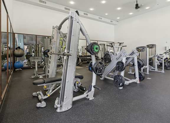 A gym with a variety of equipment including a leg press machine at The Kitt at Warner Center Apartments, Woodland Hills, CA