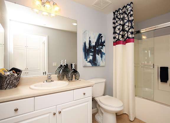 A bathroom with a white toilet, sink, and shower. at The Kitt at Warner Center Apartments, Woodland Hills, CA