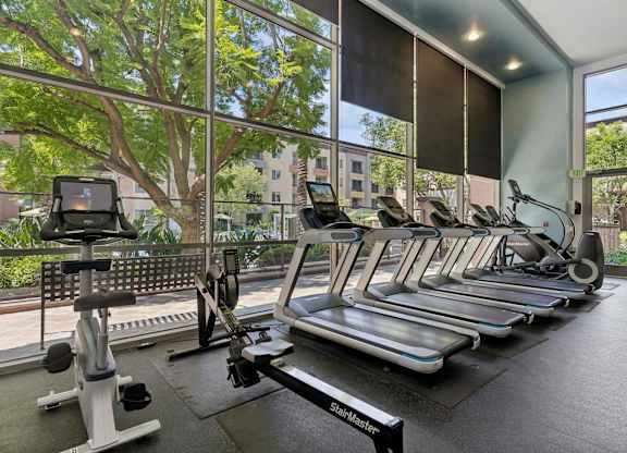 A gym with treadmills, elliptical machines, and a rowing machine at The Kitt at Warner Center Apartments, Woodland Hills, CA, 91303