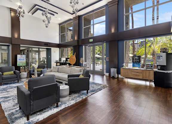 A large room with a lot of furniture and a view of trees outside the windows at The Kitt at Warner Center Apartments, Woodland Hills