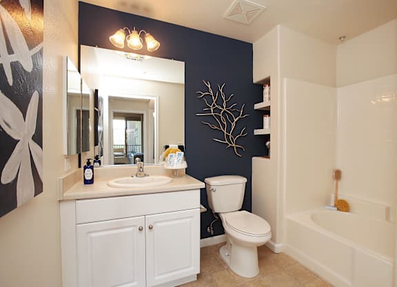 A white bathroom with a toilet, sink, and bathtub at The Kitt at Warner Center Apartments, Woodland Hills 91303