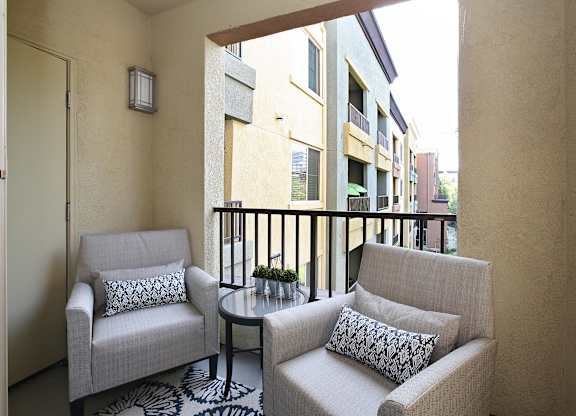 A balcony with two chairs and a table. at The Kitt at Warner Center Apartments, Woodland Hills, CA