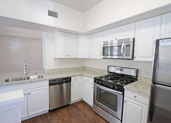 A kitchen with white cabinets and stainless steel appliances at The Kitt at Warner Center Apartments, California, 91303