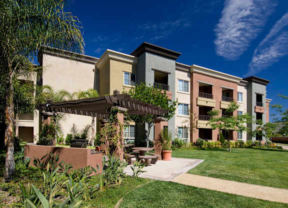 Apartment complex with a green lawn in front at The Kitt at Warner Center Apartments, California