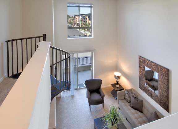 A living room with a couch, chair, and a small table with a lamp on it at The Kitt at Warner Center Apartments, Woodland Hills, CA
