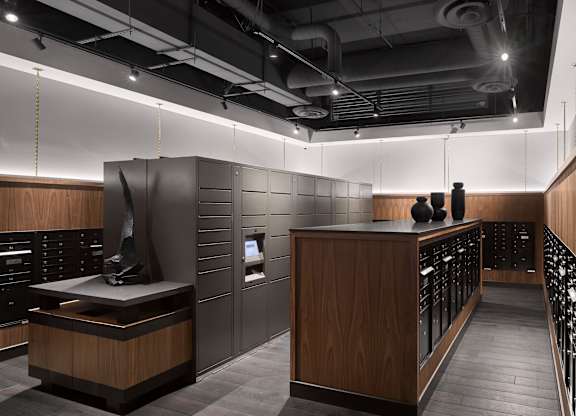 A modern office lobby with a reception desk and two people standing behind it.