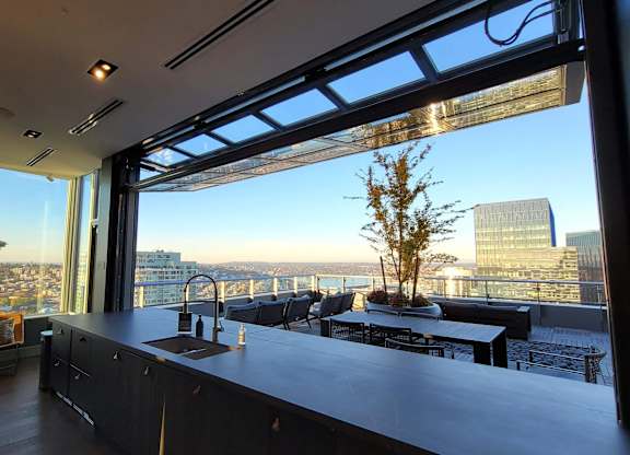 A modern kitchen with a view of the cityscape outside the large windows.
