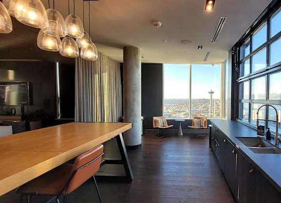 A modern kitchen with a long wooden table and a view of the city.