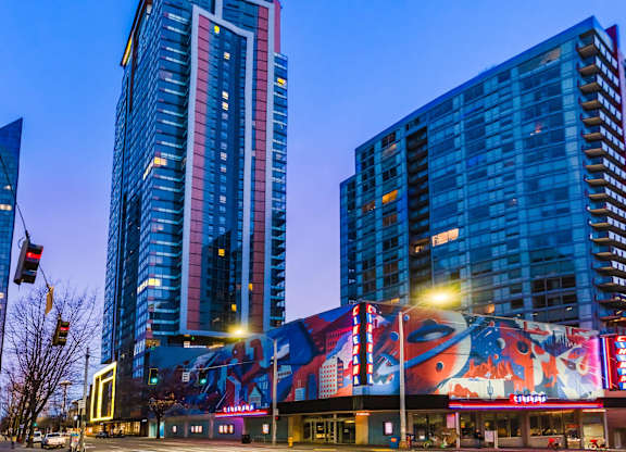 A city street with a large building featuring a colorful mural on the side.