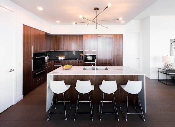 A modern kitchen with a long white table and white chairs.